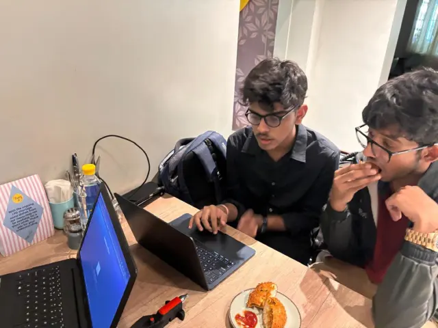 Adithya at a laptop with a teammate looking on, the CAD open on screen