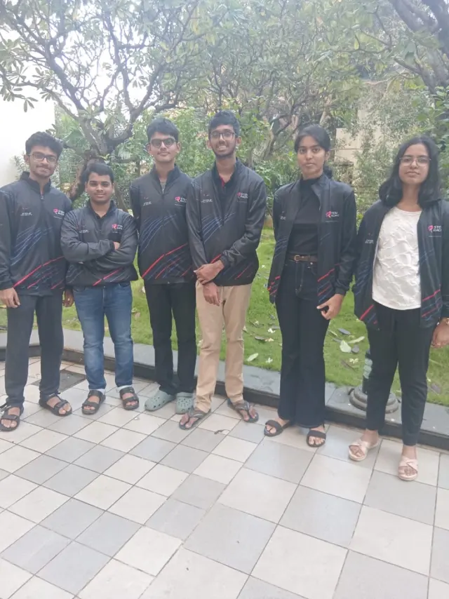 The six-member team standing together outside in black jackets