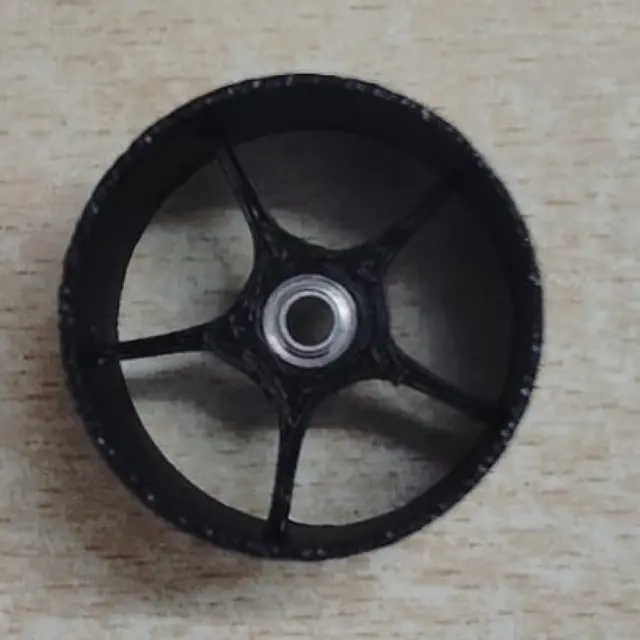 A printed black PETG wheel with its bearing